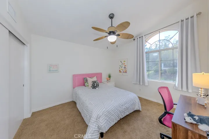 View of the second upstairs bedroom with ceiling fan and west view of the street.