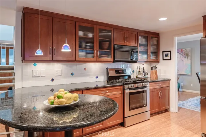 Gleaming granite, shiny stainless, and artsy glass pendant lighting