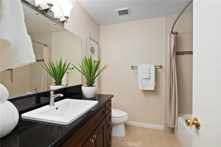 Remodeled Full Bath with tub/shower overhead, attractive wood cabinetry & granite countertop