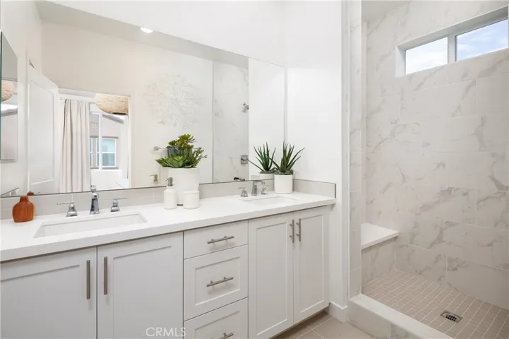 The primary bathroom is highly upgraded with quartz counters, a decorative tile backsplash, and the shower with full height upgraded tile surround.