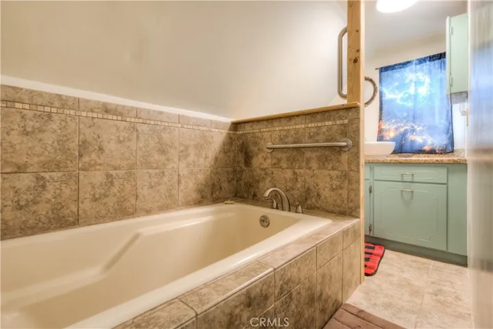 Soaking tub enclosed in tile with grab bar.