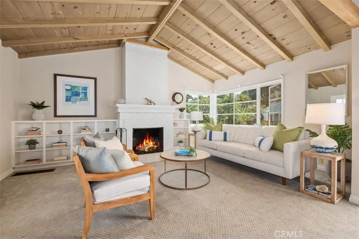 Large living room space with vaulted ceilings and fireplace and built in book shelves.