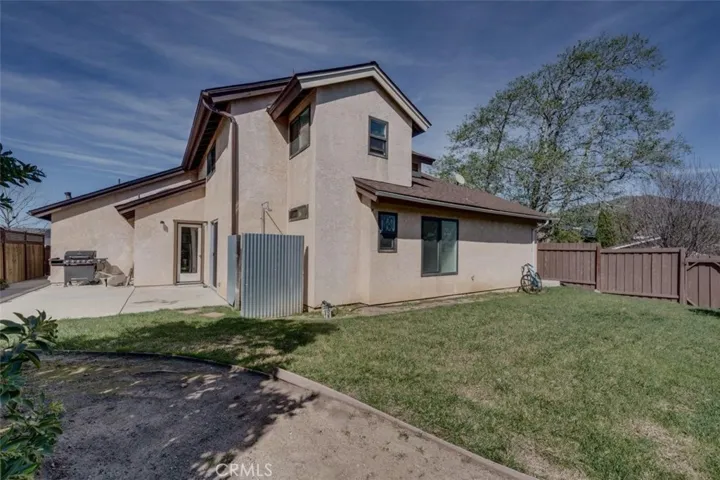 Spacious wrap-around back yard with new fence section and shade tree.
