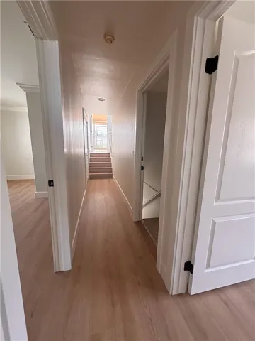 Hall view: 2nd bedroom is on the left; 3rd bedroom is the first door on the right; second door to the right leads to steps down to garage. Straight ahead: steps leading to primary en suite bedroom. Laundry closet is on the left just before the steps.
