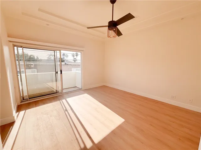 Primary bedroom with volume tray ceiling and ceiling fan -view to sliding door and deck