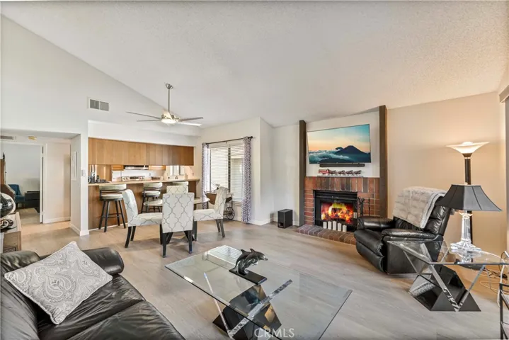 Spacious living room features luxury vinyl flooring, vaulted ceilings, a new ceiling fan and cozy fireplace.