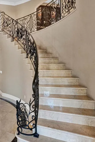 Let's head upstairs, and what a beautiful staircase it is! Stone treads and risers and a magnificent custom scrolled wrought iron staircase system. It's just beautiful.