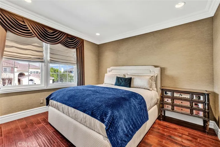 This bedroom is the first half of the Jack 'n Jill room with rich wood flooring, crown molding, recessed lighting and custom window coverings.
