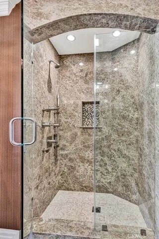 The stone shower in the suite has rimless glass doors, a niche for supplies and a multi-head shower system.