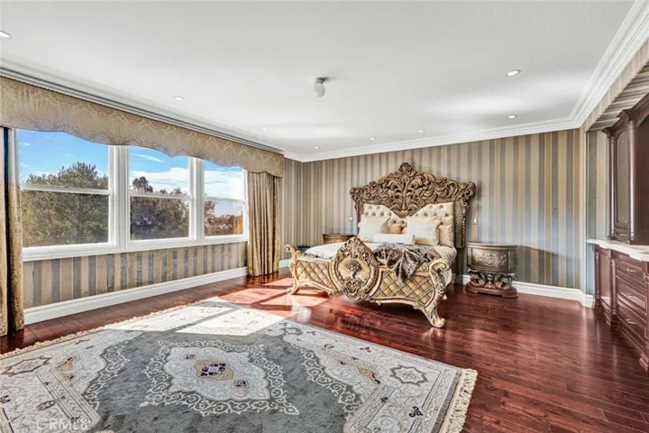 The owner's suite on the second level has beautiful wood flooring and a built-in dresser. There's recessed lighting and a ceiling light fixture as well as the stately crown molding sculpted baseboards that are found throughout the home.