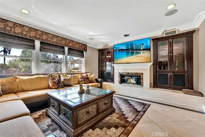 A closer look at the stone faced fireplace with custom mantle and built-in entertainment center. Custom window coverings are found throughout the home.