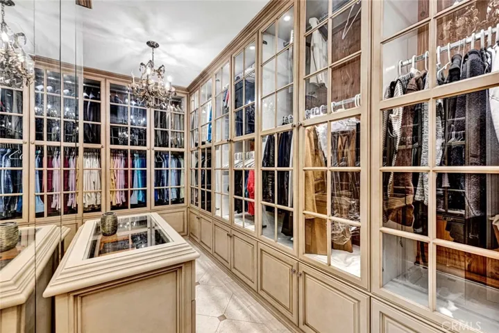 This huge walk-in closet has a furniture grade organizers system with glass doors to keep your close dust free 2 center dressers and chandeliers.