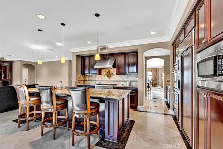 This kitchen will delight your inner gourmet! There's abundant cabinet and counter top space for food prep on a grand scale. Note the bar seating at the island and the pendant lighting above.