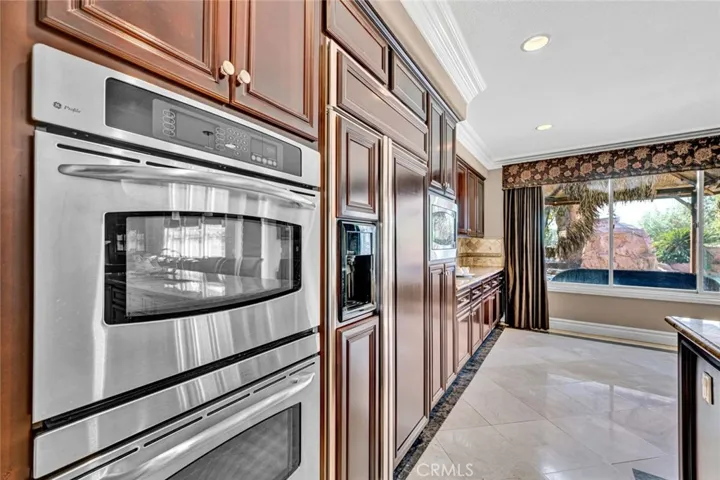 The double ovens, built-in refrigerator and dishwasher with cabinet facing and microwave are GE Profile. Continuing the cabinets and counter tops down the side wall of the breakfast room adds so much work and storage space.