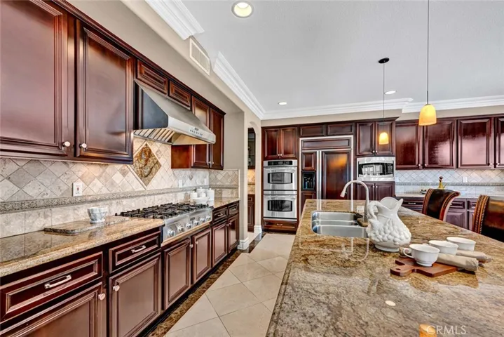 Another view of this wonderful kitchen showing the Thermador 6 burner cooptop and range hood and all the work space is this busy part of the kitchen.