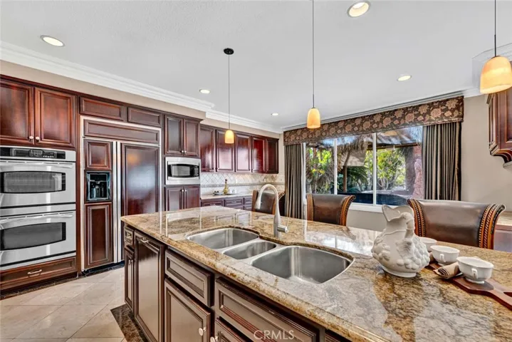 The triple compartment stainless steel sink and cabinet faced dishwasher are located in the huge island.