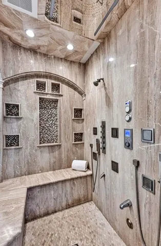 At the top of the shower and picture, the mirrored panel is covered with rain shower spouts. And there's a large bench to sit and enjoy it!
