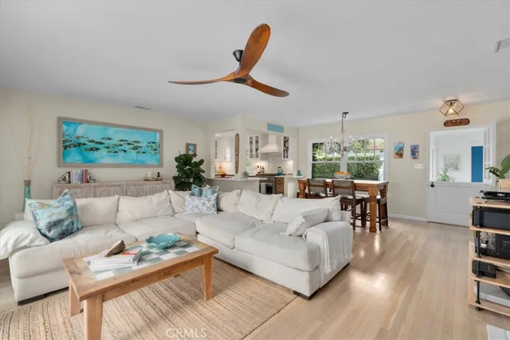 View of the living room, dining area and kitchen from the other wall. Ceiling fan and big windows and doors for airflow