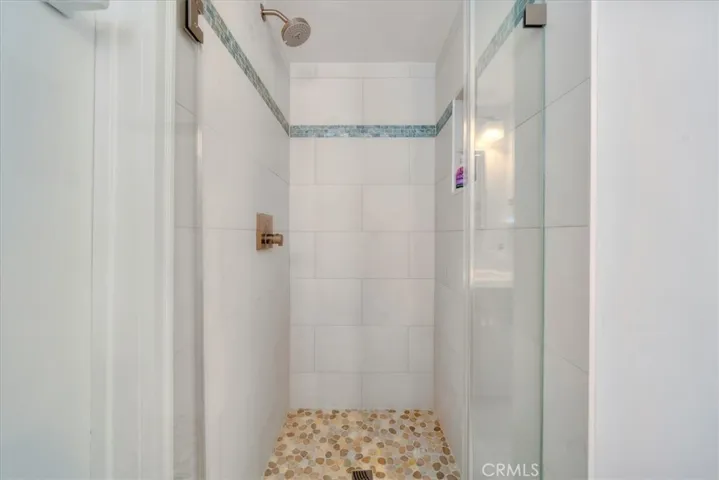 Updated shower in bedroom 3 with bronze shower fixture, a stone floor and glass doors
