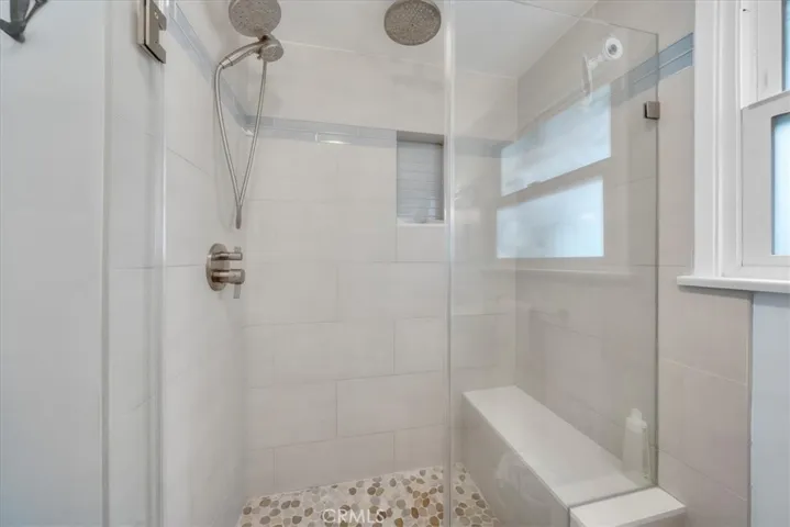 Updated shower in bathroom with in shower bench and glass doors