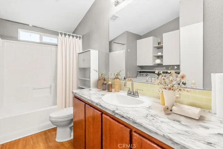 Bathroom tub/shower with washer and dryer and cabinet storage - items are staged online