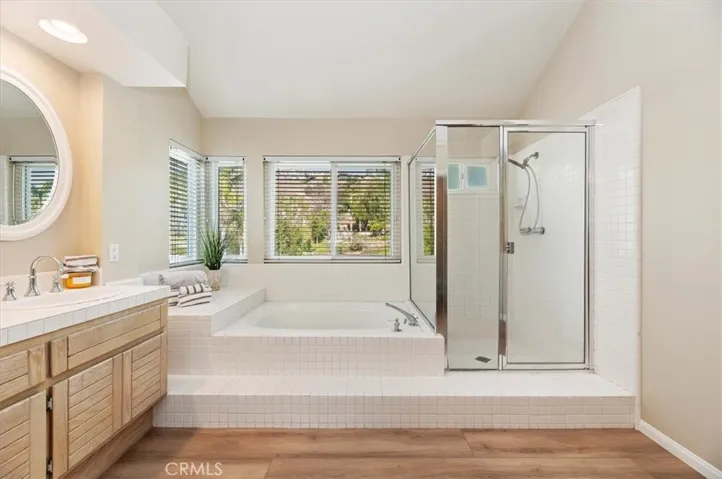 View of soaking tub and walk-in shower. Views out of windows of backyard and hills