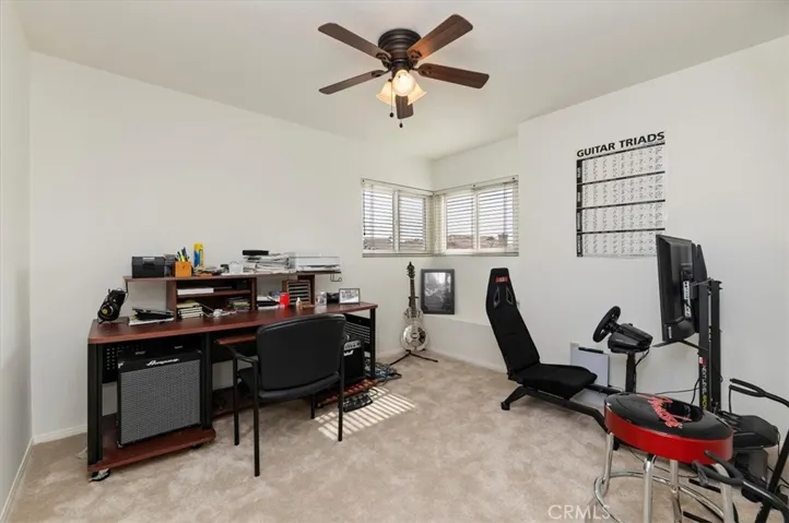 3rd Bedroom with window seat and closet with organizer and mirrored wardrobe doors. Currently used as music room and office. Notice ceiling fan and new carpet