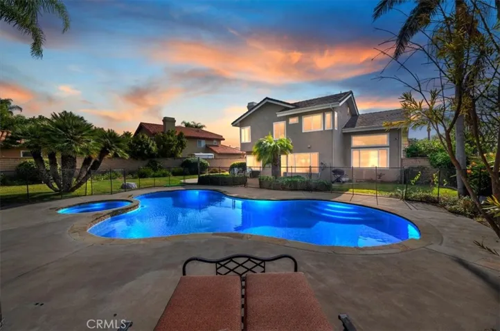 View of the home and sparkling pool and spa. The pool and spa has a safety fence for children. The fencing is removal if desired