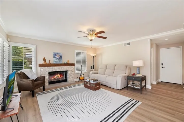 Close up of cozy fireplace recently remodeled with stone and wood mantle, crown moldings, shutters, large baseboards, freshly painted and new flooring