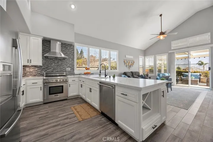 Open kitchen with professional grade Thermador gas stove and Thermador dishwasher.