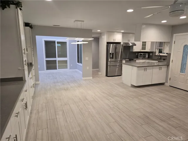 other corner of living room into dining room, enclosed atrium and kitchen