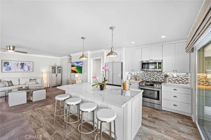 Well-appointed kitchen with stainless steel appliances, marble countertops and custom backsplash