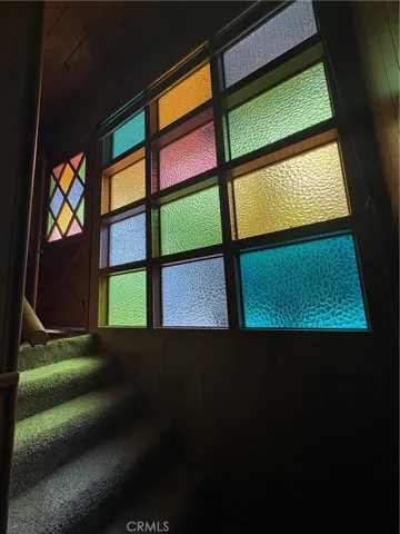 Front Door Entry with Vintage Stained Glass, Adjacent Stained Glass Fixed Window Panels, and Stairway to Lower Level Living Area