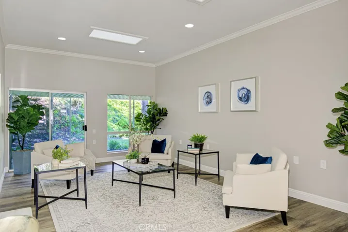 Spacious living room features a high 11' ceiling and easily accommodates various configurations of large furnishings. Direct access to the rear patio via a glass slider. Note the additional upgrades including smooth ceilings, recessed lighting, crown molding and baseboards.