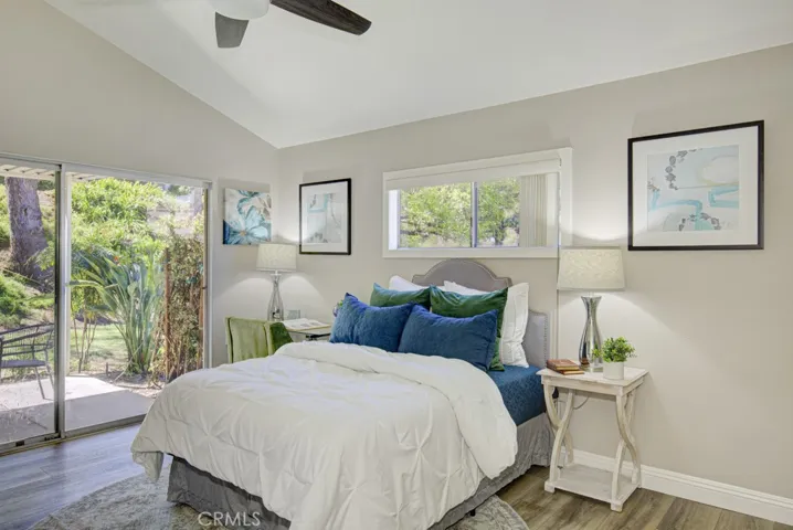 Right-side primary bedroom. Note vaulted ceiling, additional window added above the bed, ceiling fan and the direct access to the rear patio.