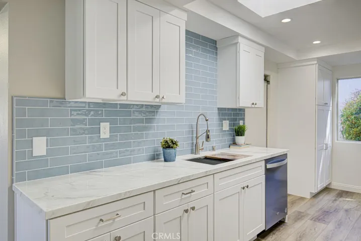 Upgraded kitchen features ample cabinet storage capacity, quartz countertops, soft-close drawers, large pots and pans drawers, stainless steel appliances and a large skylight. Access door to garage can be partially seen at rear.