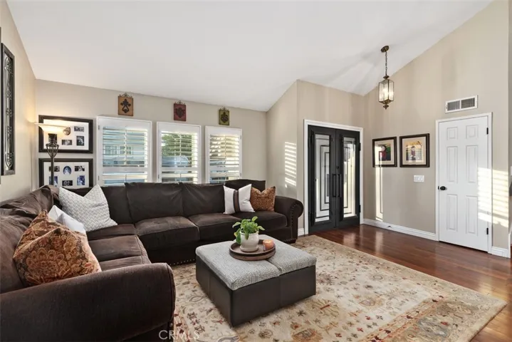 Beautiful living room with wood flooring, custom front doors & double pane window throughout.