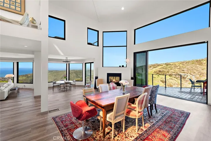  Double-height ceilings and an abundance of large windows lend an open, light-filled ambiance to a great room with fireplace and ocean and canyon views.