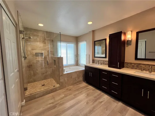 Primary en suite bathroom with walk-in shower, separate soaking tub, dual sinks, espresso cabinetry, and walk-in closet