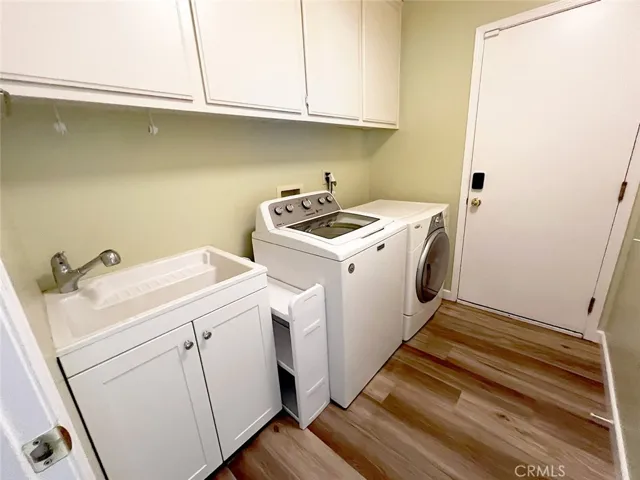 Separate laundry room downstairs with utility sink and cabinets