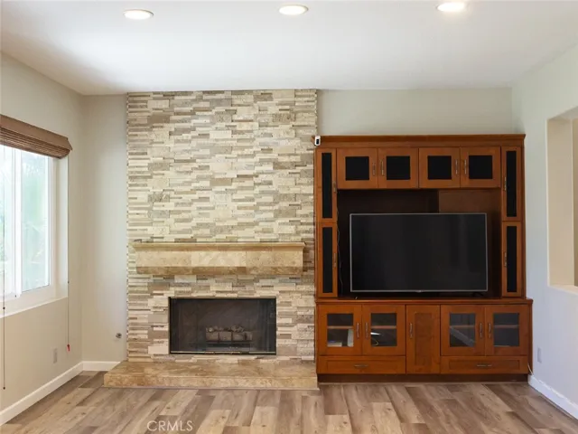 Family room with stacked stone fireplace and entertainment center that opens to the chef's kitchen
