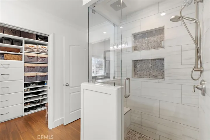 private ensuite bath featuring a spacious walk-in shower with tile surround and a frameless glass door.