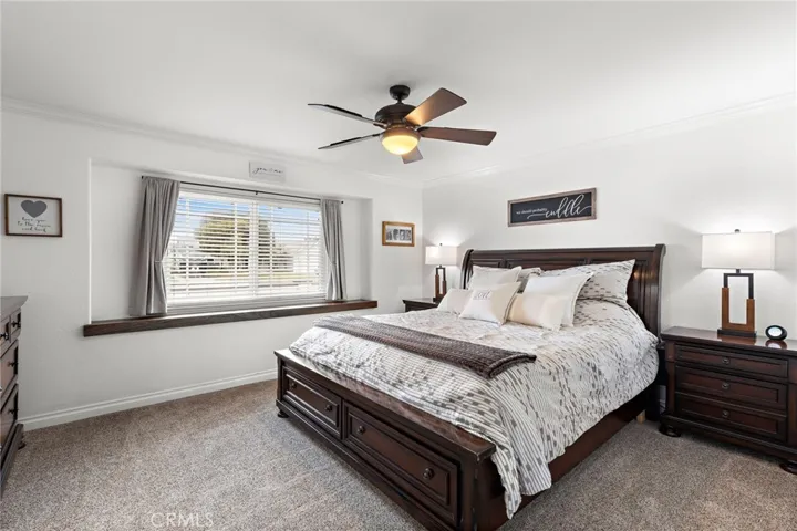 The primary suite offers a peaceful retreat with a custom wood window ledge, crown molding, a center ceiling fan/light combo