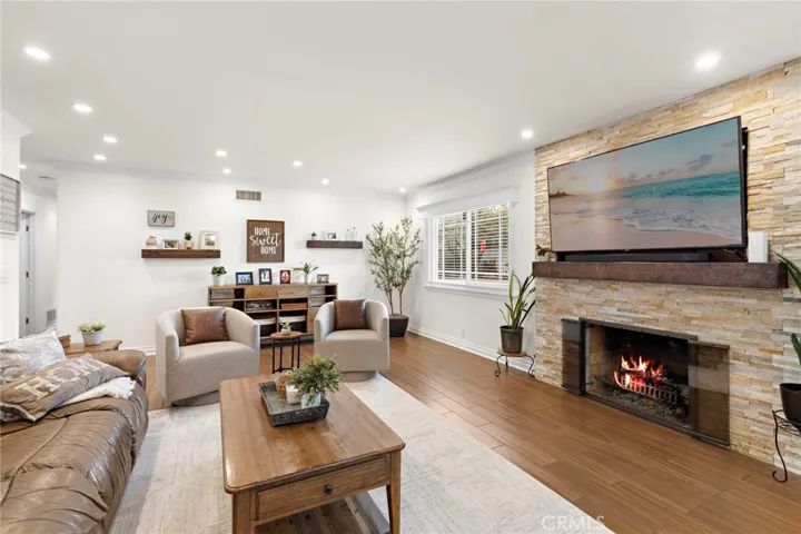 The open-concept living areas include a cozy living room with a stacked stone fireplace and glass doors leading to the backyard oasis.