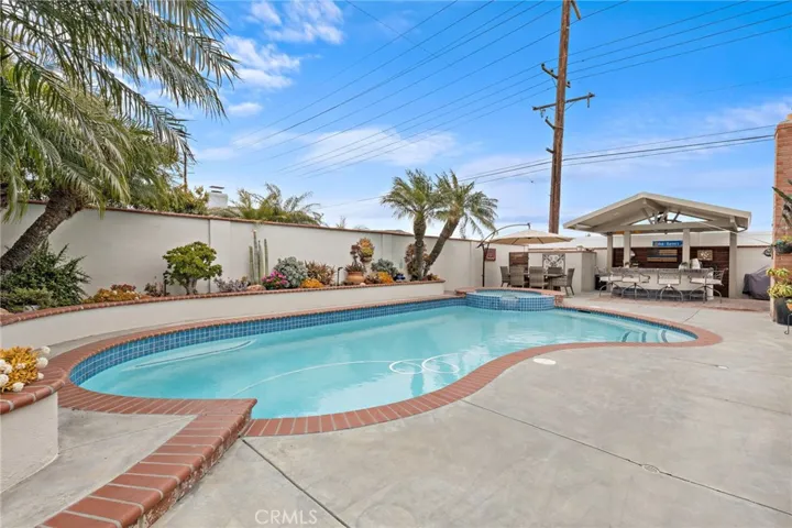 Stucco walls with brick toppers, raised planters with lush palms, and vibrant succulent gardens complete this stunning outdoor space.