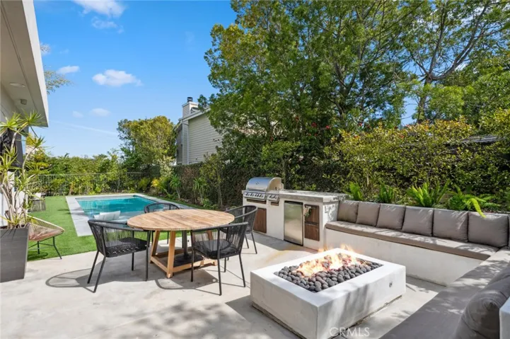 The private, fully fenced yard is an entertainer’s paradise, featuring multiple seating areas, a fire pit, lush landscaping, and an impressive pool with an adjoining spa, perfect for relaxation.