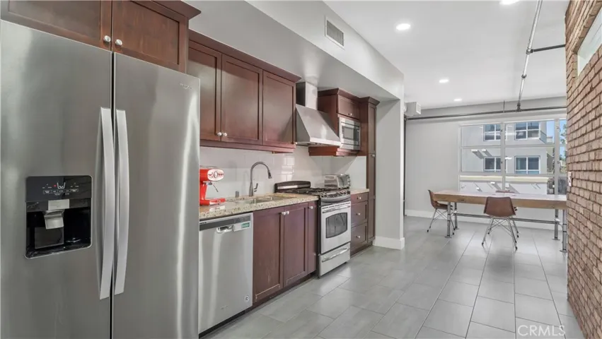 Kitchen with refrigerator, dishwasher and stainless steel sink and hood.  Gas range and microwave.
