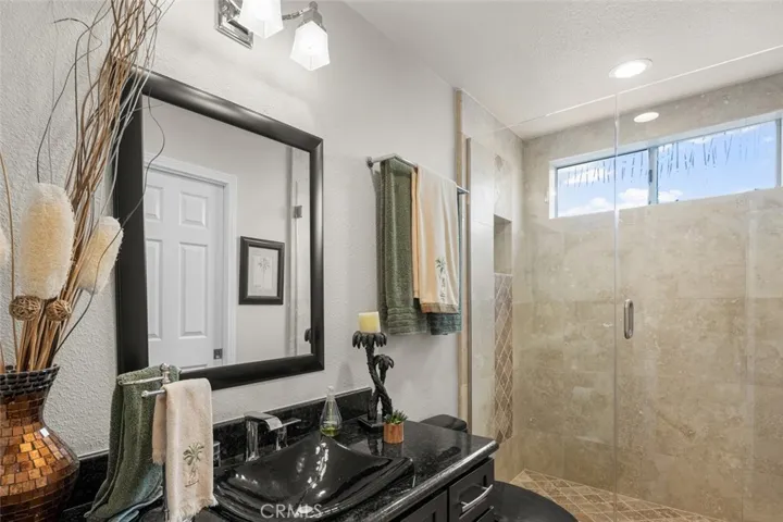 Downstairs full bath all remodeled. Tub removed and replaced with custom stone shower, custom glass doors, newer vanity, mirror and vanity lighting.