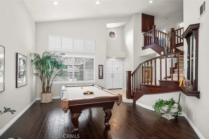 Formal living room is currently adorned with a pool table and formal dining area behind currently a cozy sofa gathering spot to watch the pool game.