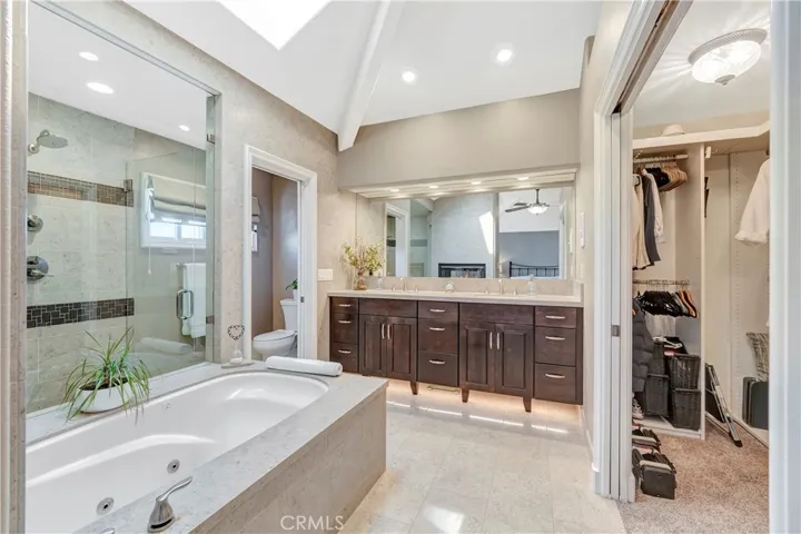 Primary en-suite bathroom retreat with heated floors, complete with a large walk-in shower and separate jacuzzi tub, along with dual vanity sinks and a custom walk-in closet